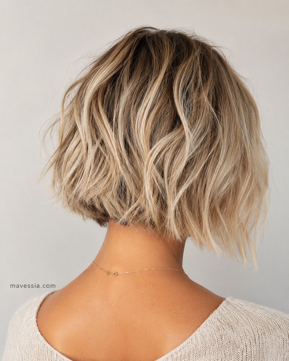 Back view of a tousled blonde choppy bob haircut with a clean, wavy perimeter line