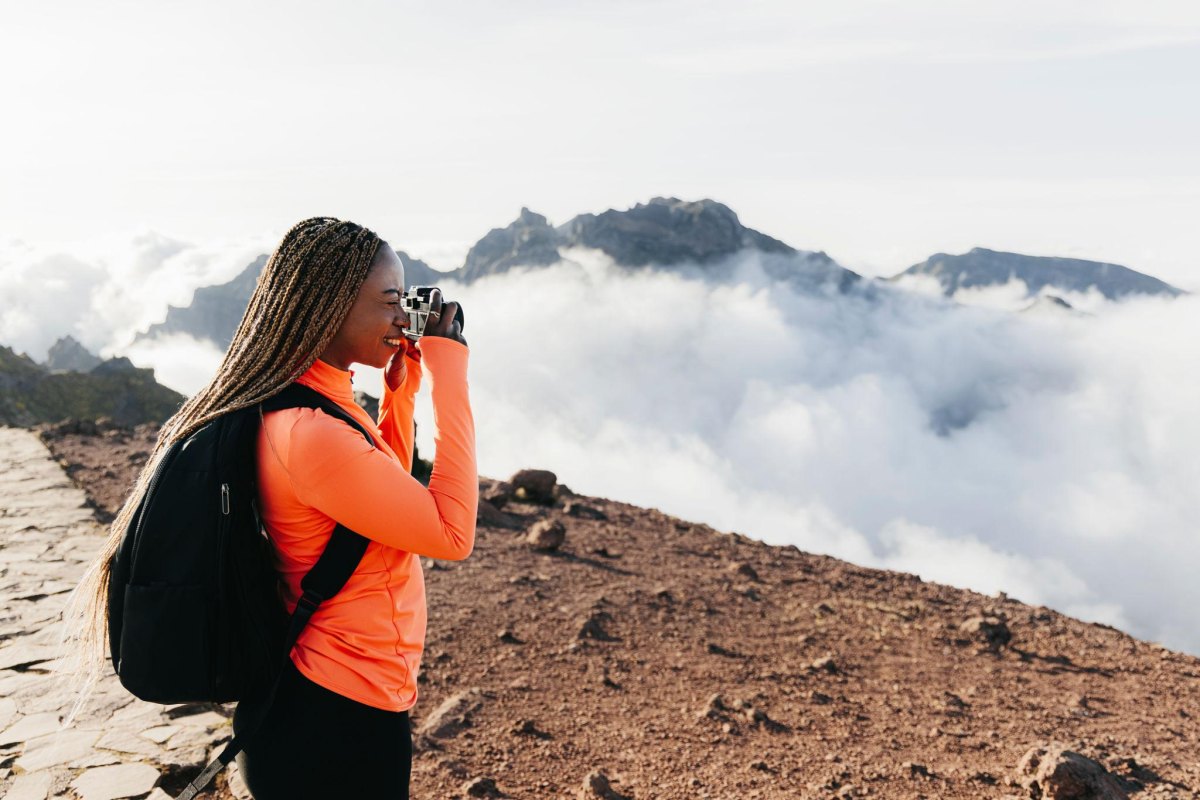 Woman photographing mountain landscape